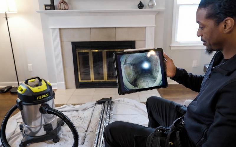 Modern chimney technician viewing inspection camera feed on monitor