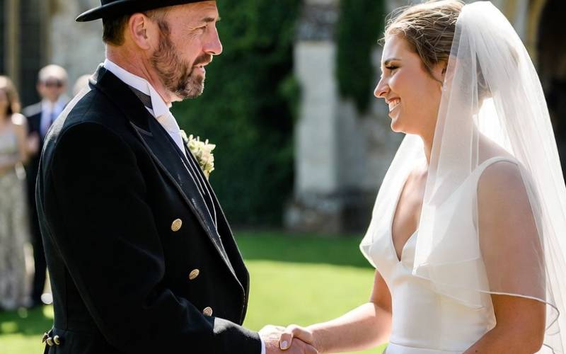 Chimney sweep in top hat shaking hands with bride outside church